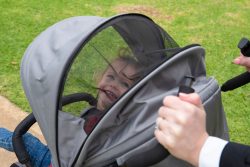 child peeking through mesh sunroof of stroller